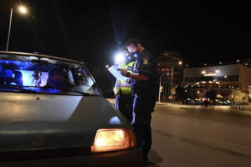 Police check the documents of a driver during the lockdown to contain the spread of COVID-19 in the northern city of Thessaloniki, Greece, Tuesday, Nov. 3, 2020. A lockdown has come into effect in northern Greece, with the southeastern European country joining the list of the continent's nations tightening restrictions to restrain rapidly increasing coronavirus infections. (AP Photo/Giannis Papanikos)