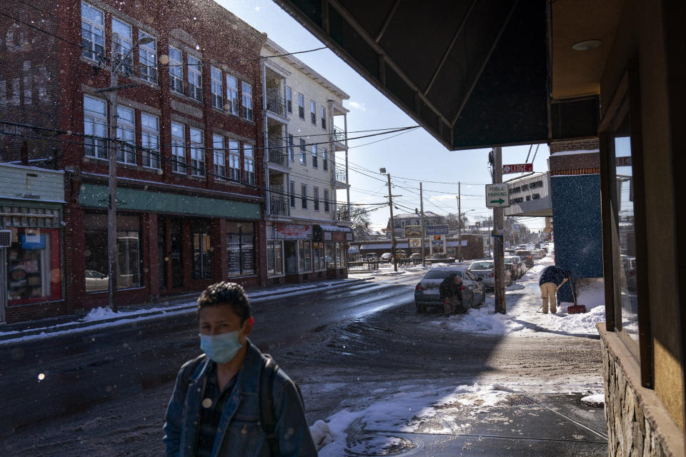 A man shovels snow along a busy commercial street in Central Falls, R.I., Saturday Feb. 20, 2021. Residents in the hard-hit community of Central Falls live in dense rows of triple-decker homes and apartment complexes and are the workforce for the states capital of Providence to the south. (AP Photo/David Goldman)