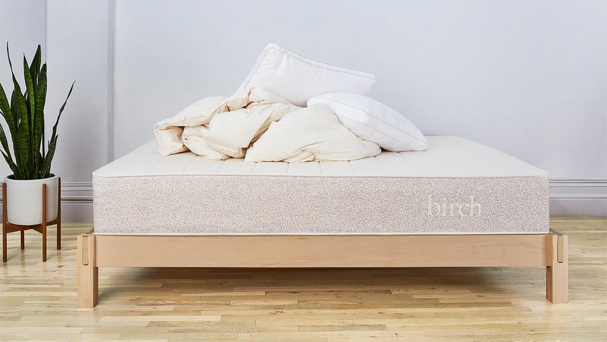  The Birch Natural Mattress on a bed with some bedding piled on top of it 