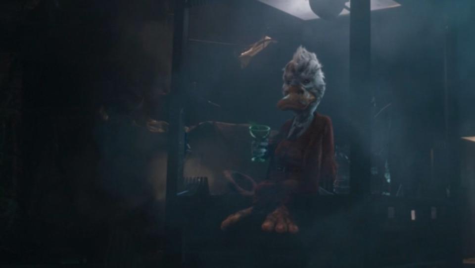 Howard the Duck in a red suit drinks a cocktail in his broken glass cage in Guardians of the Galaxy Vol. 1