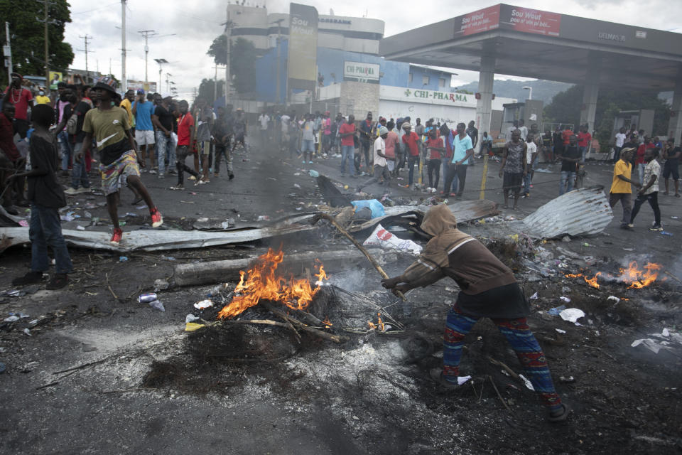 Demonstrators mill around a barricade set up to protest against fuel price hikes and to demand that Haitian Prime Minister Ariel Henry step down, in Port-au-Prince, Haiti, Monday, Sept. 19, 2022. (AP Photo/Odelyn Joseph)