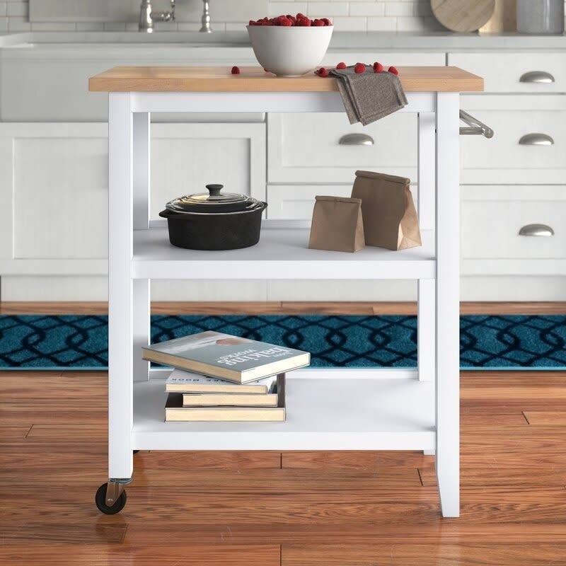 rolling kitchen cart with two open shelves filled with books and cookware