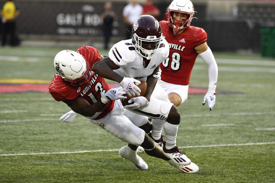 Louisville defensive back Qwynnterrio Cole (12) attempts to strip the ball from Eastern Kentucky's Jaden Smith, center, during the first half of an NCAA college football game in Louisville, Ky., Saturday, Sept. 11, 2021. (AP Photo/Timothy D. Easley)