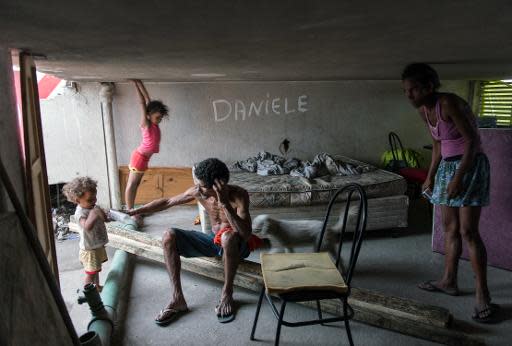 A family takes a rest inside their hut under construction after invading a deserted property belonging to a telephone company in Rio de Janeiro, Brazil, on April 4, 2014. According to the new dwellers the property, which includes offices and warehouses has remained abandoned for more than 20 years. AFP PHOTO/YASUYOSHI CHIBA (AFP | Yasuyoshi Chiba)