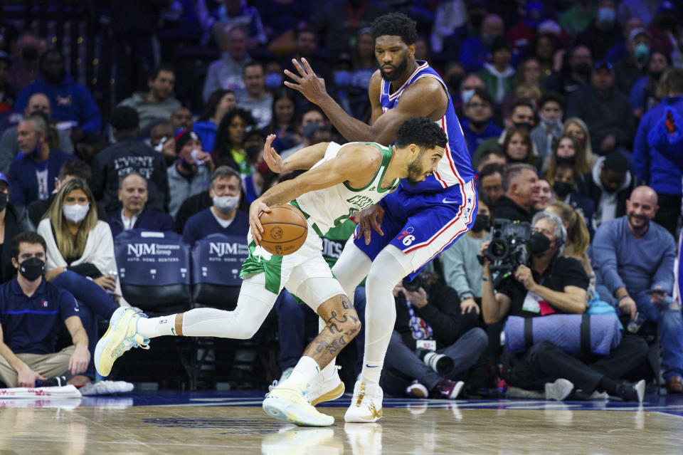 Boston Celtics' Jayson Tatum, left, drives to the basket against Philadelphia 76ers' Joel Embiid, right, during the first half of an NBA basketball game, Friday, Jan. 14, 2022, in Philadelphia. (AP Photo/Chris Szagola)