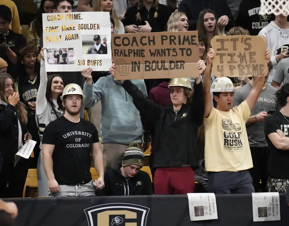 Fans hold up signs encouraging Jackson State head football coach Deion Sanders to take the head football coach opening at Colorado in the first half of an NCAA college basketball game as Colorado hosts Arizona State, Thursday, Dec. 1, 2022, in Boulder, Colo. (AP Photo/David Zalubowski)