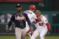 Washington Nationals' Juan Soto (22) and Trea Turner celebrate in front of Atlanta Braves second baseman Ozzie Albies after Soto hit a game-winning single in the ninth inning of an opening day baseball game at Nationals Park, Tuesday, April 6, 2021, in Washington. Victor Robles scored on the play, and Washington won 6-5. (AP Photo/Alex Brandon)