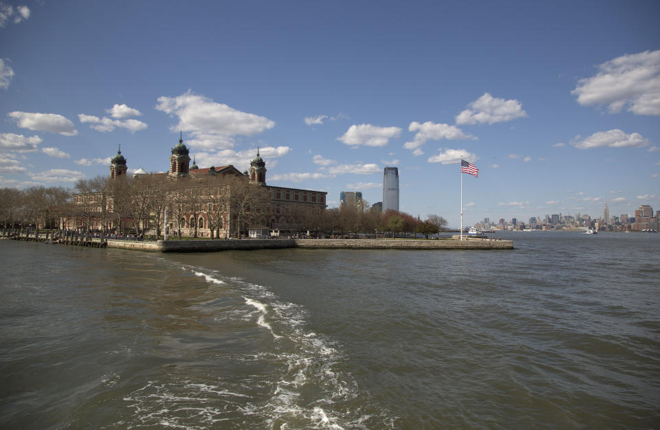 FILE - The wake from a ferry is seen trailing the boat as it leaves Ellis Island for Manhattan, on April 29, 2015, in New York. The location is featured in a collection of mini-essays by American writers published online by the Frommer's guidebook company about places they believe helped shape and define America. (AP Photo/Julie Jacobson, File)