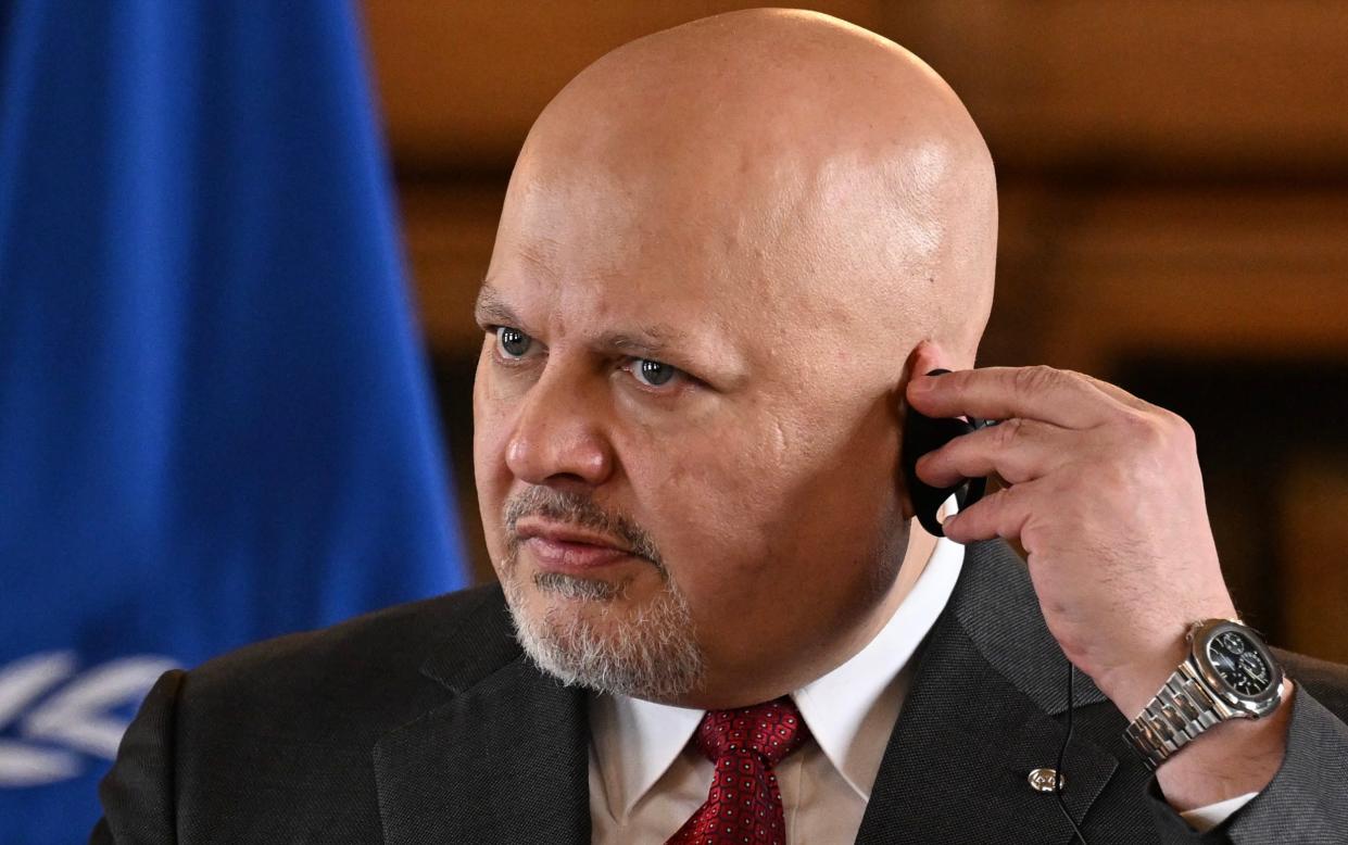 Karim Khan adjusting an earpiece for simultaneous translation in front of a UN flag