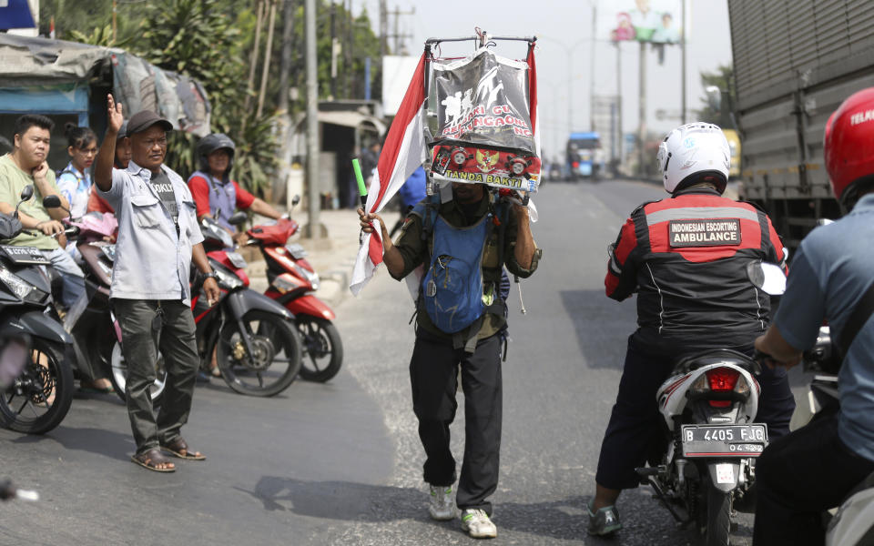 Medi Bastoni, 43, walks backwards in Bekasi, outskirt of Jakarta, Indonesia, Thursday, Aug, 22, 2019. The Indonesian man is walking over 700-kilometer (430-mile) backward from his home in eastern Java to the country's capital to draw awareness of deforestation.(AP Photo/Achmad Ibrahim)