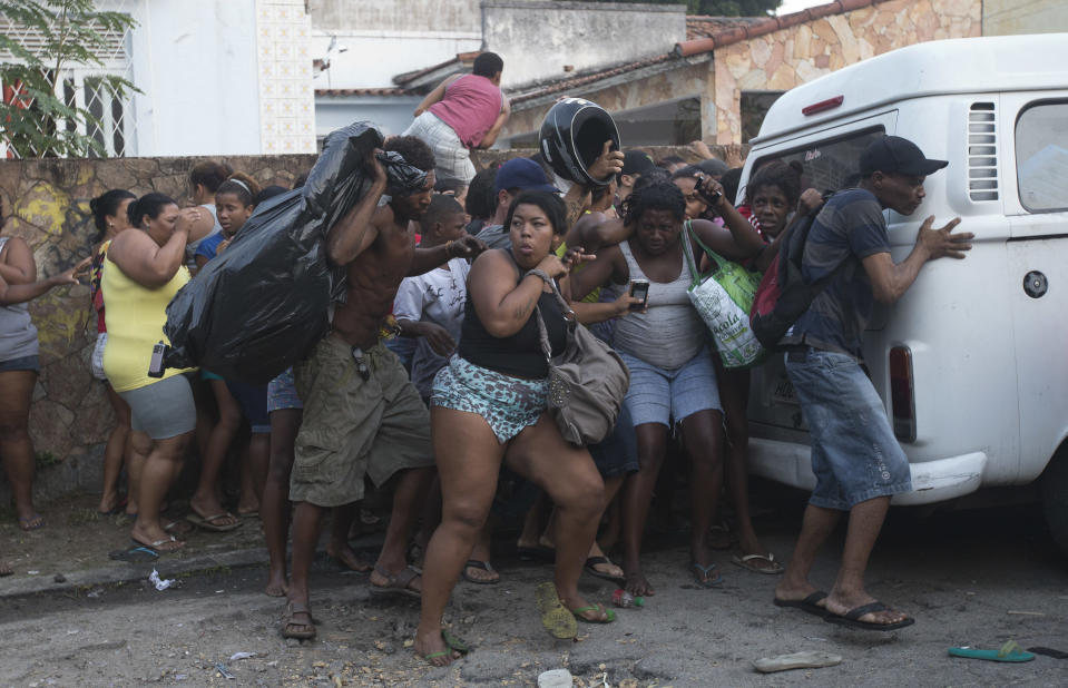 Invasores de terreno se parapetan de las granadas de aturdimiento y gases lacrimógenos durante un desalojo en Río de Janeiro el 11 de abril del 2014. (AP Foto/Silvia Izquierdo)