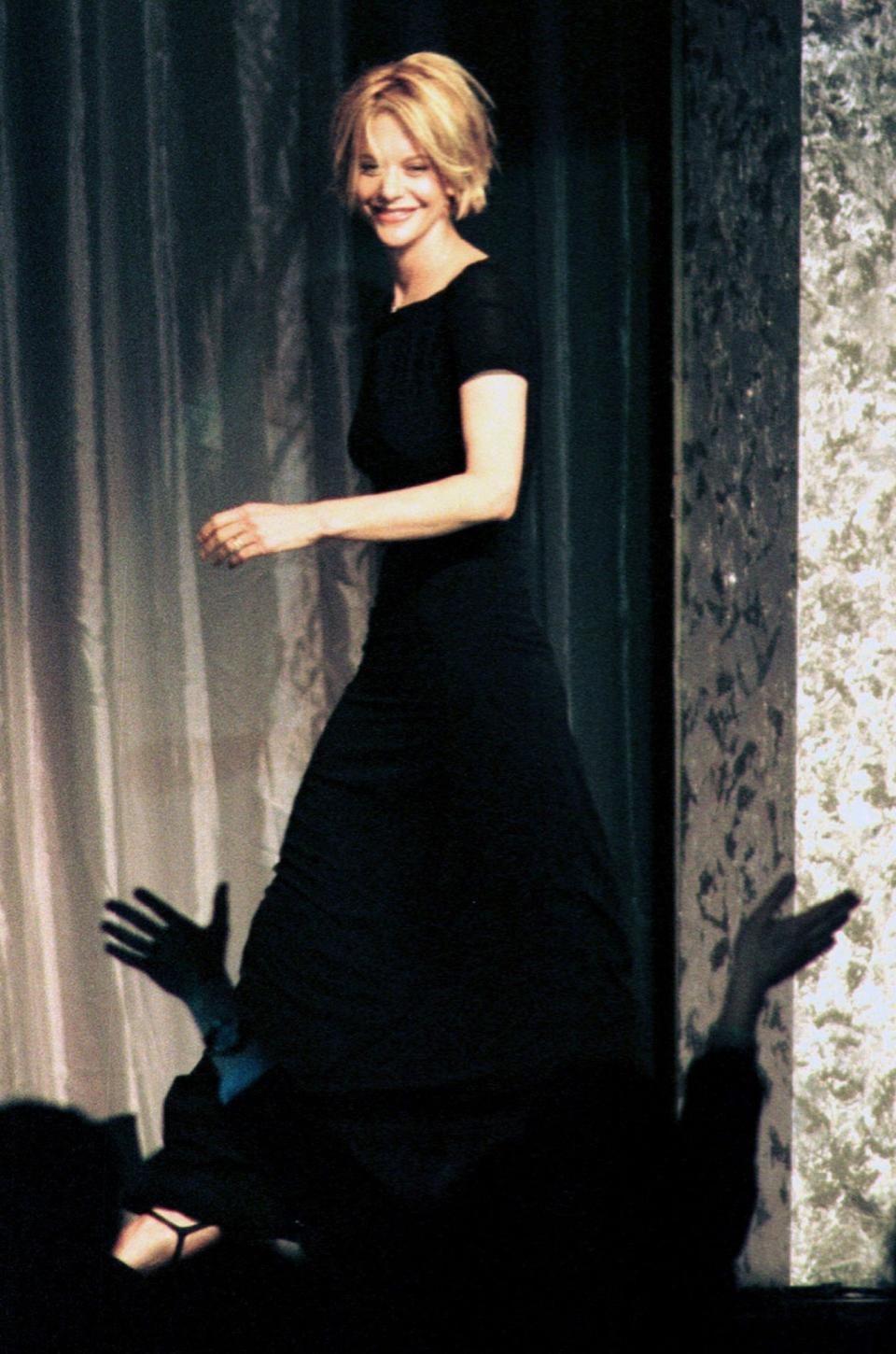 Actress Meg Ryan laughs as a fan cheers for her with outstretched arms while she makes her entrance to receive the Actress of the Year Award at the National Association of Theater Owners/ShoWest Awards