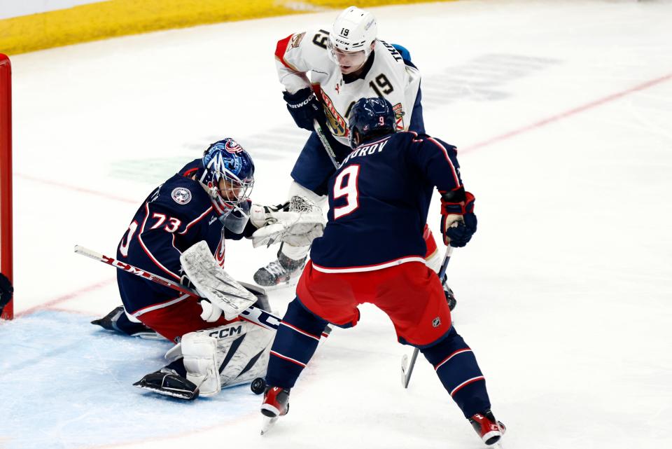 Columbus Blue Jackets goalie Jet Greaves, left, stops a shot by Florida Panthers forward Matthew Tkachuk (19) in front of Blue Jackets defenseman Ivan Provorov (9) during the third period of an NHL hockey game in Columbus, Ohio, Sunday, Dec. 10, 2023. (AP Photo/Paul Vernon)