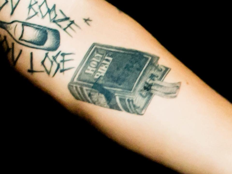 A holy bible tattoo, seen on Harry Styles' left forearm.