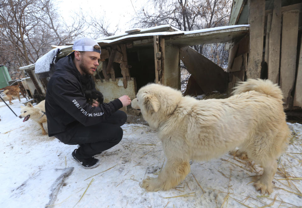 American freestyle skier Gus Kenworthy plays with a dog at a dog meat farm in Siheung, South Korea. (AP)