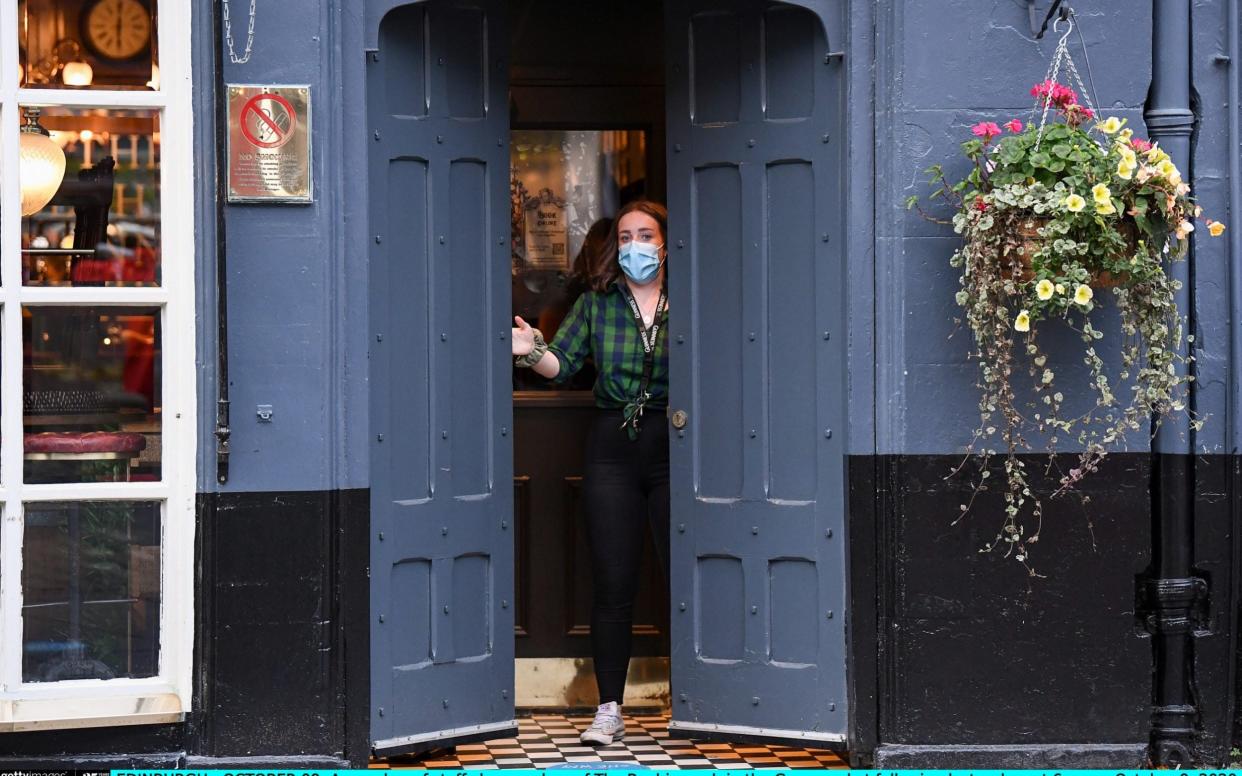 A member of staff closes the door of the Beehive pub in Edinburgh. Pubs and restaurants in the central belt of Scotland shut for a fortnight from October 9 - Jeff J Mitchell/Getty Images Europe