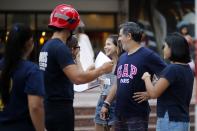 In this Jan. 13, 2019 photo, firefighter Daniel Rodriguez sells calendars to a family, in Asuncion, Paraguay. The idea for the calendar arose during a photography class taught by Spanish photographer Jose Maria Guerrero. (AP Photo/Jorge Saenz)