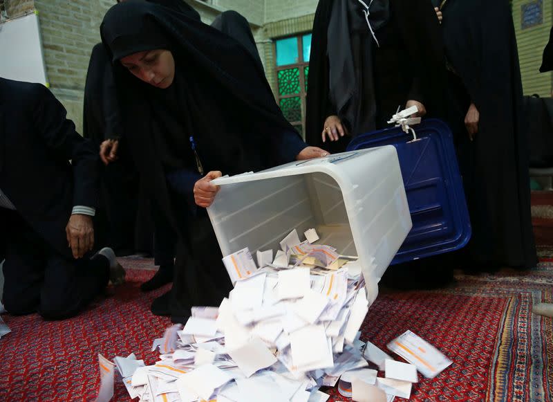 Poll workers empty full ballot boxes after the parliamentary election voting time ended in Tehran