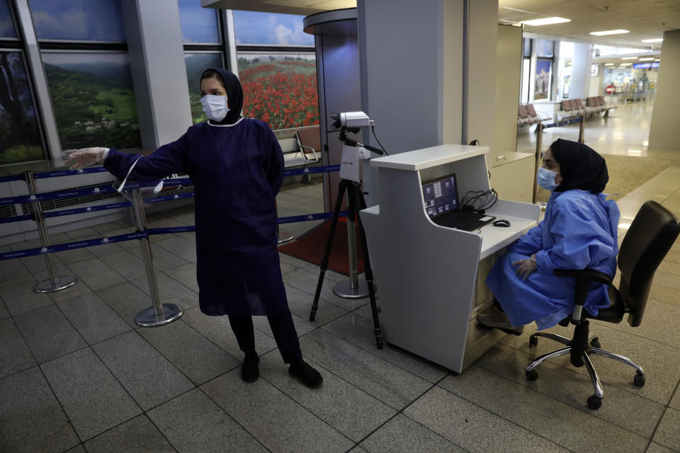 Two health workers wait to check the temperatures of arriving passengers and collect declaration forms, at Tehran's Imam Khomeini airport, Iran, Friday, July 17, 2020. The first Emirates flight arrived in Iran after nearly 5 months of suspension of the most airliners flights to the country due to the coronavirus outbreak, as Iranian officials at the airport say they are doing everything possible to ensure passengers are not infected, and isolate those with symptoms. (AP Photo/Vahid Salemi)