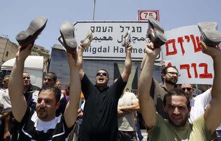 Israeli Arab demonstrators hold up shoes during a protest in Nazareth, Israel's largest Arab town, against a rally by Jewish ultranationalists calling to draft Israeli Arabs, in this July 15, 2012 file photo. REUTERS/Ammar Awad/Files