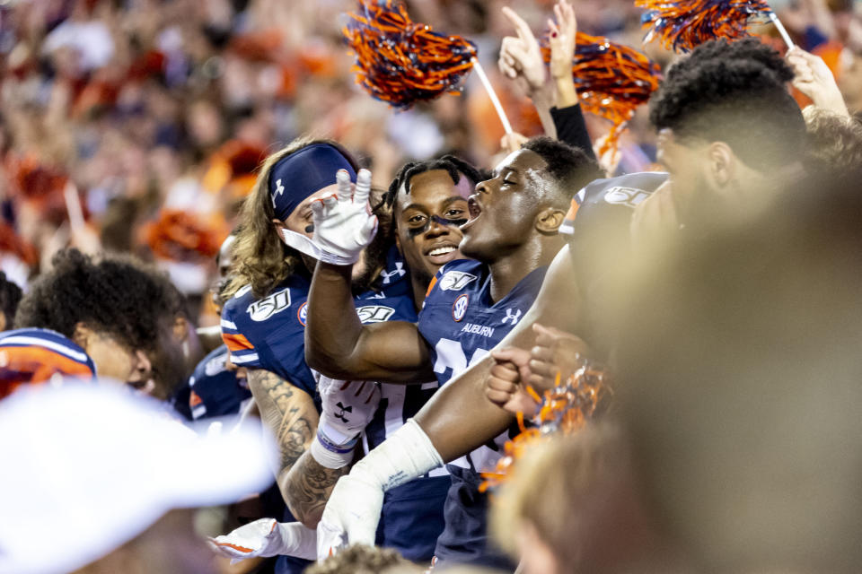 Auburn players sit in the student section as fans take the field to celebrate an upset of Alabama after an NCAA college football game, Saturday, Nov. 30, 2019, in Auburn, Ala. (AP Photo/Vasha Hunt)