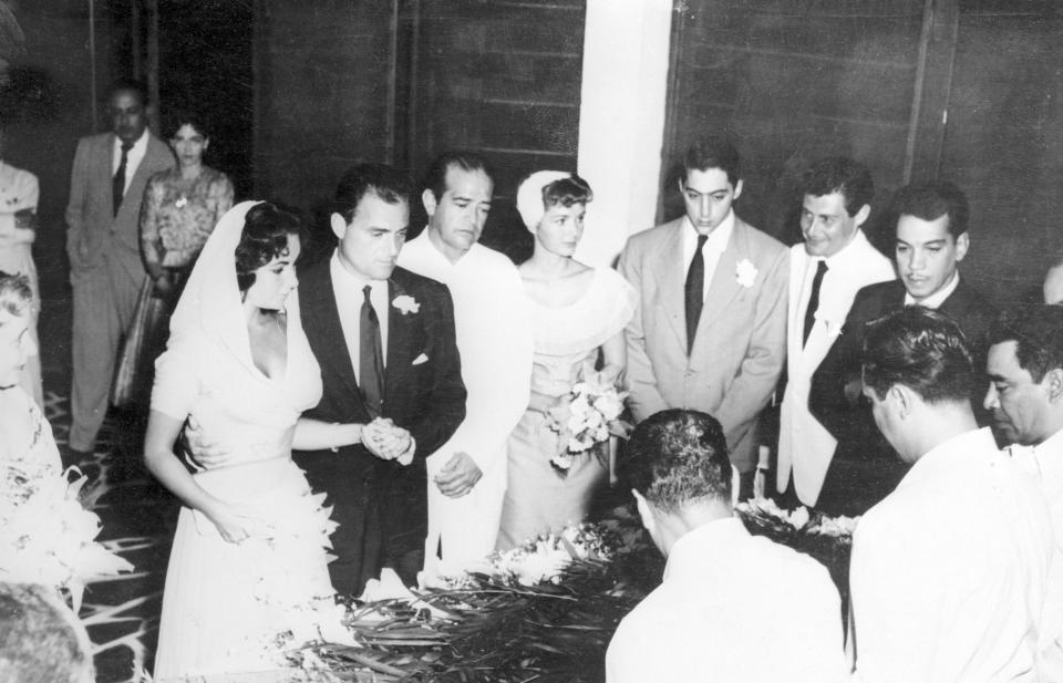 Elizabeth Taylor and film producer Mike Todd’s 1957 wedding. Debbie Reynolds, matron of honor, is holding the flowers in the center of the photo, while Eddie Fisher is to her right in the white suit. (Photo: Getty Images)