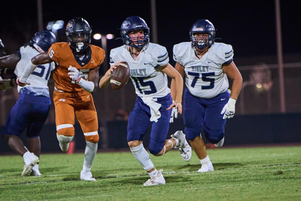 Higley Knights quarterback Gunner Fagrell (15) scrambles to find an open teammate as Desert Edge Scorpions defensive end Deshawn Warner (15) closes in at Desert Edge High School in Goodyear on Friday, Sept. 15, 2023.