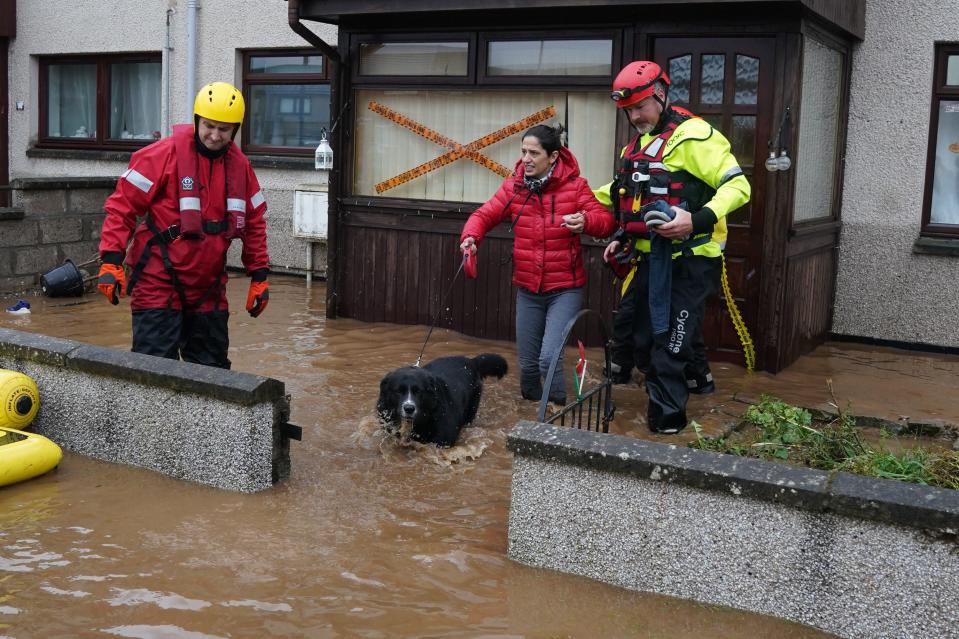 A member of the emergency services helps resident from a house in Brechin (PA)