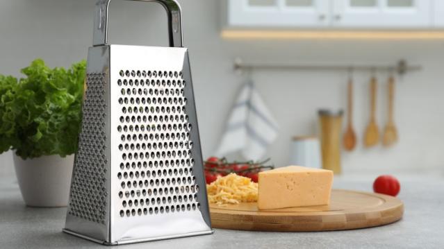 Cheese Beeing Grated In The Kitchen Stock Photo - Download Image