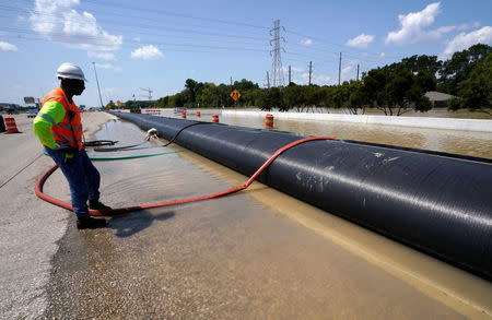 A Texas Department of Transportation worker monitors a temporary water filled dam keeping Harvey floodwaters from getting onto highway I-10 in Houston, Texas August 31, 2017. REUTERS/Rick Wilking