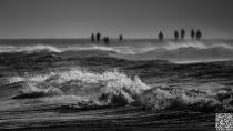 Shark Alarm by heimibe<br><br>The bright evening sun allowed the short exposure time in this picture. Stormy weather whipped the waves against the light. The arc-shaped beach course made this perspective possible from which I was able to capture the beach strollers in the background and with the tapering beach waves in the foreground, even without getting wet feets. By: heimibe