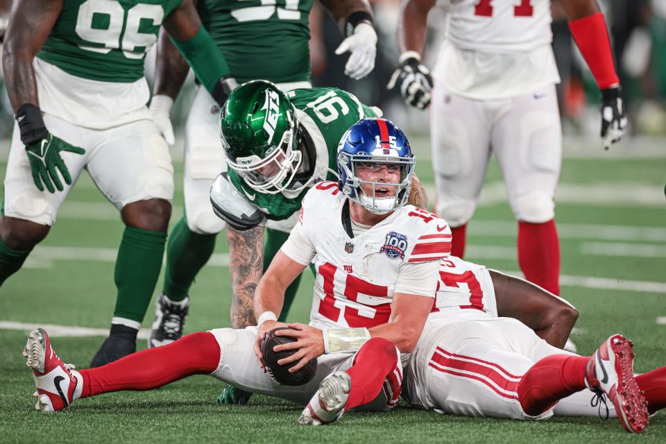 Aug 24, 2024; East Rutherford, New Jersey, USA; New York Giants quarterback Tommy DeVito (15) reacts after being sacked during the second half by New York Jets defensive end Braiden McGregor (91) at MetLife Stadium. Mandatory Credit: Vincent Carchietta-USA TODAY Sports