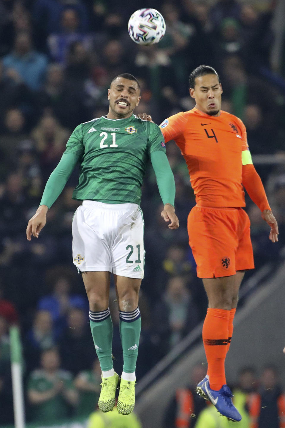 Northern Ireland's Josh Magennis jumps for the ball with Netherlands' Virgil Van Dijk, right, during the Euro 2020 group C qualifying soccer match between Northern Ireland and the Netherlands at Windsor Park, Belfast, Northern Ireland, Saturday, Nov. 16, 2019. (AP Photo/Peter Morrison)