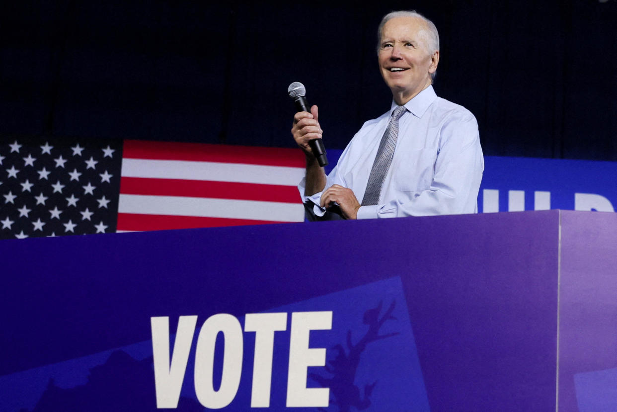 President Biden, a broad smile on his face, takes the microphone.