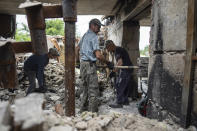 Volunteers clear rubbish on the ground floor of Zhanna and Serhiy Dynaeva's house which was destroyed by Russian bombardment, in the village of Novoselivka, near Chernihiv, Ukraine, on Saturday, Aug. 13, 2022. Residents in many heavily-damaged areas in Ukraine have set up their own initiatives to rebuild homes before the winter as international organizations rush aid to Ukraine to help with the reconstruction effort. (AP Photo/Evgeniy Maloletka)