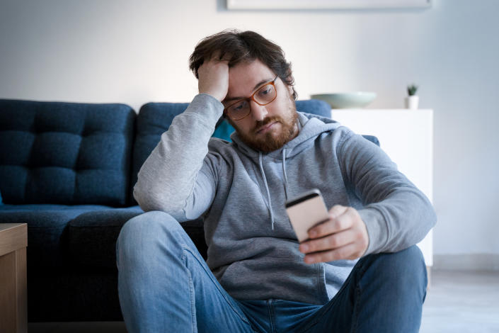 Single lonesome guy checking cell on the couch