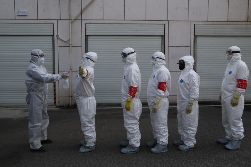 Volunteers in protective suits are being disinfected in a line in Wuhan, the epicentre of the novel coronavirus outbreak, in Hubei