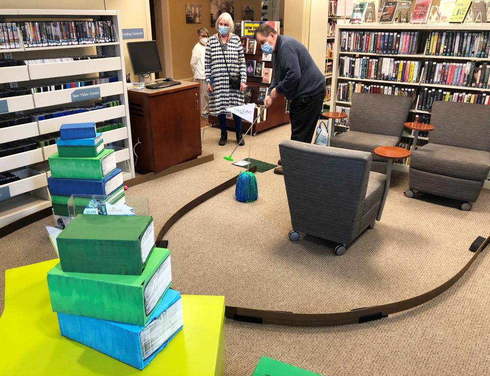 David Keefe, joined by wife Pat, tackles a challenging hole sponsored by Finger Lakes Community College at Wood Library's Friday night mini golf fundraiser, Fairway Frolic.