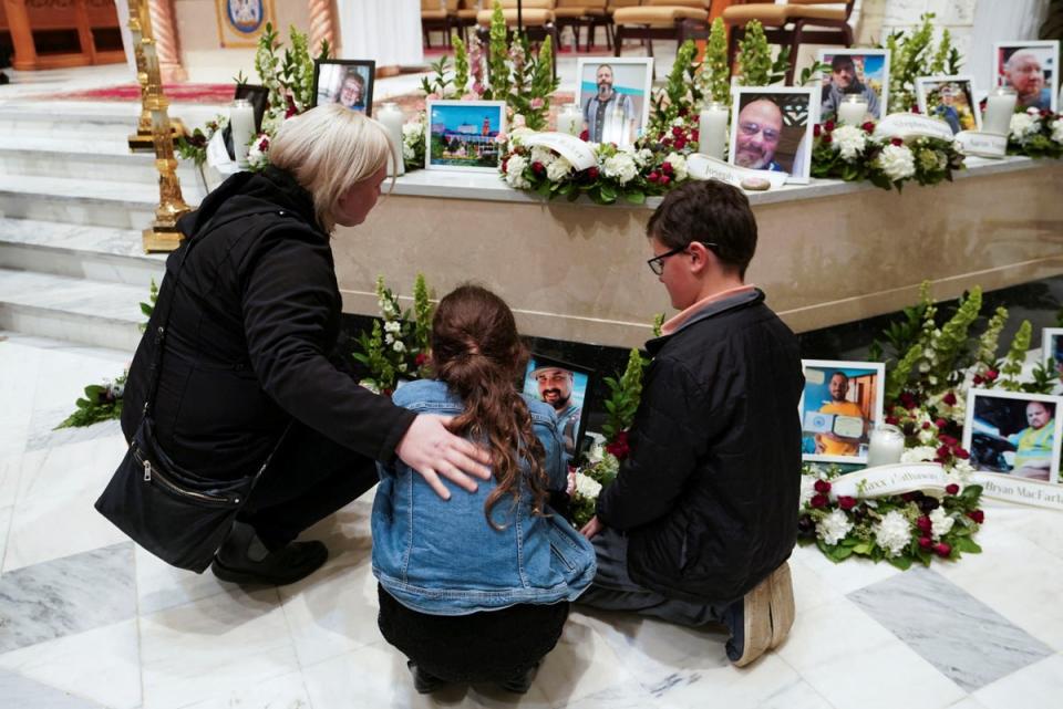 Mourners look at pictures of the victims during a vigil for the victims of the deadly mass shooting, at the Basilica of Saints Peter and Paul, in Lewiston, Maine (REUTERS)