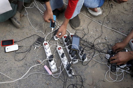 Migrants from Afghanistan charge their mobile phones, powered by a generator, at "The New Jungle" camp in Calais, France, August 4, 2015. REUTERS/Pascal Rossignol