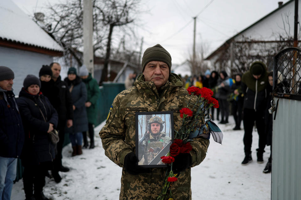 A Ukrainian serviceman holds a portrait of his brother-in-arms Volodymyr Androshchuk