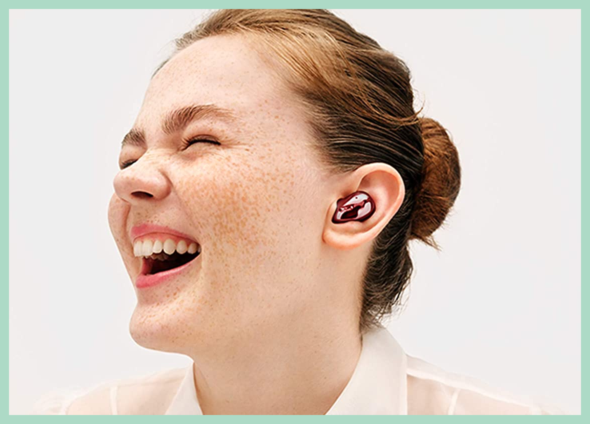 Woman smiling with red ear bud in her ear.