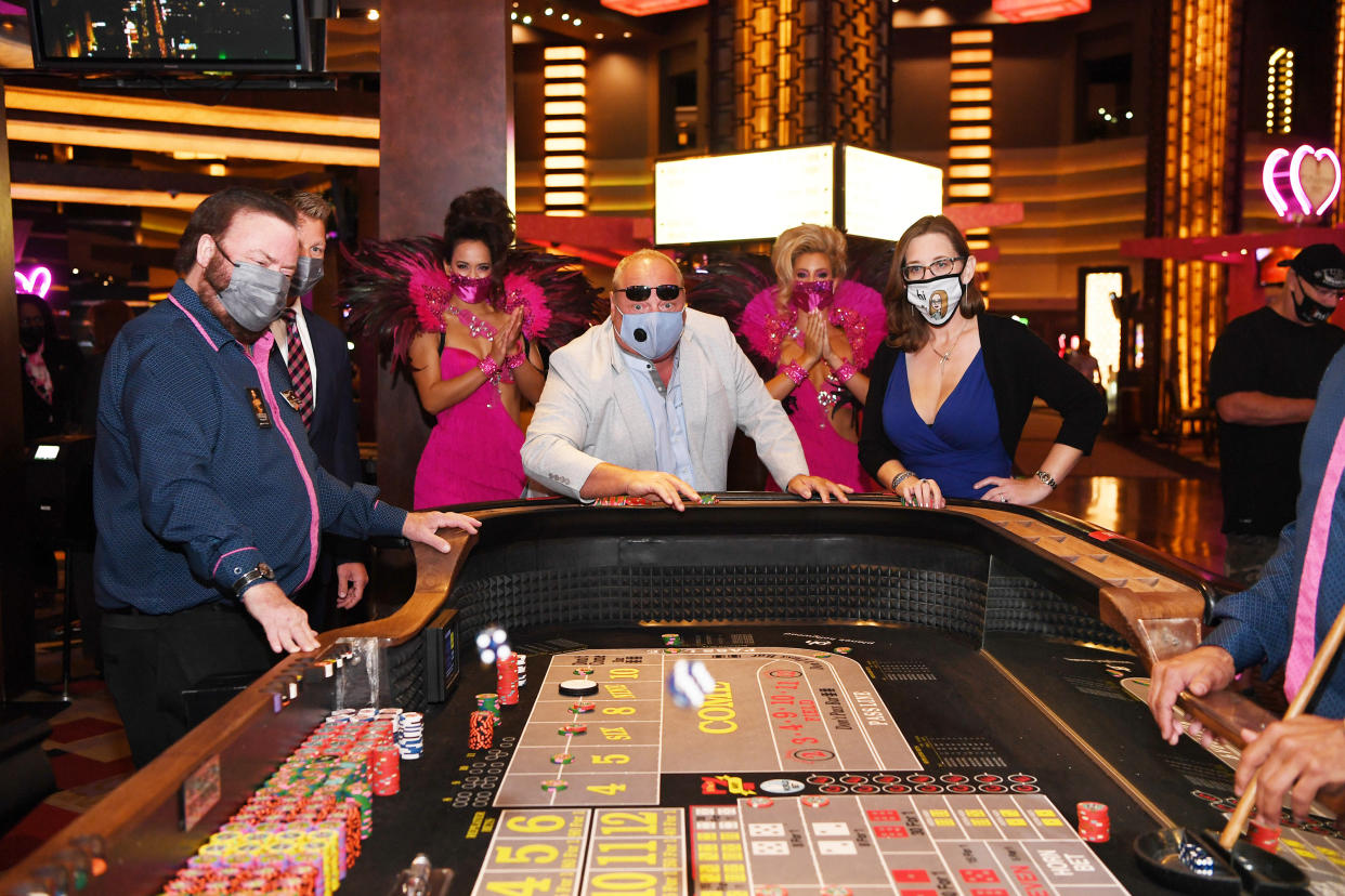 Showgirls pose for a photo with the first Caesars Rewards guests to play at a craps table at the reopening of Planet Hollywood Resort & Casino on October 8, 2020 in Las Vegas. (Photo by Denise Truscello/Getty Images for Caesars Entertainment)