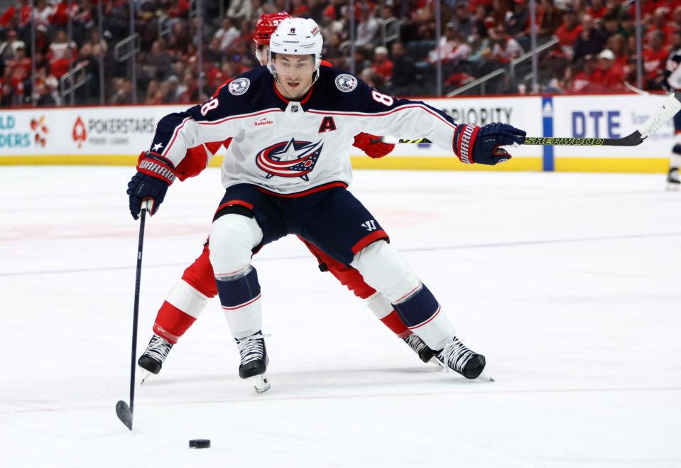 Columbus Blue Jackets defenseman Zach Werenski (8) is pursued by Detroit Red Wings right wing Alex DeBrincat during the first period of an NHL hockey game Tuesday, March 19, 2024, in Detroit. (AP Photo/Duane Burleson)