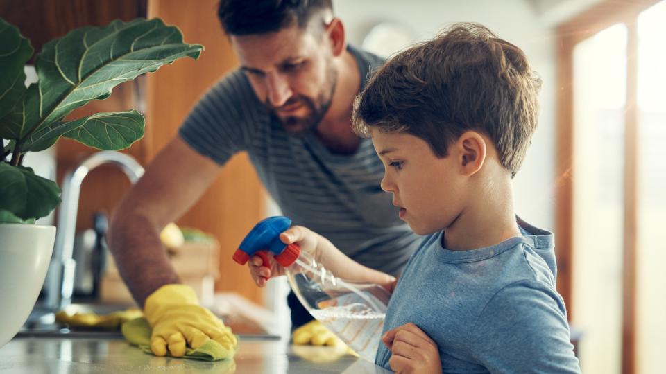 Shot of a father and son cleaning the kitchen counter together at home.