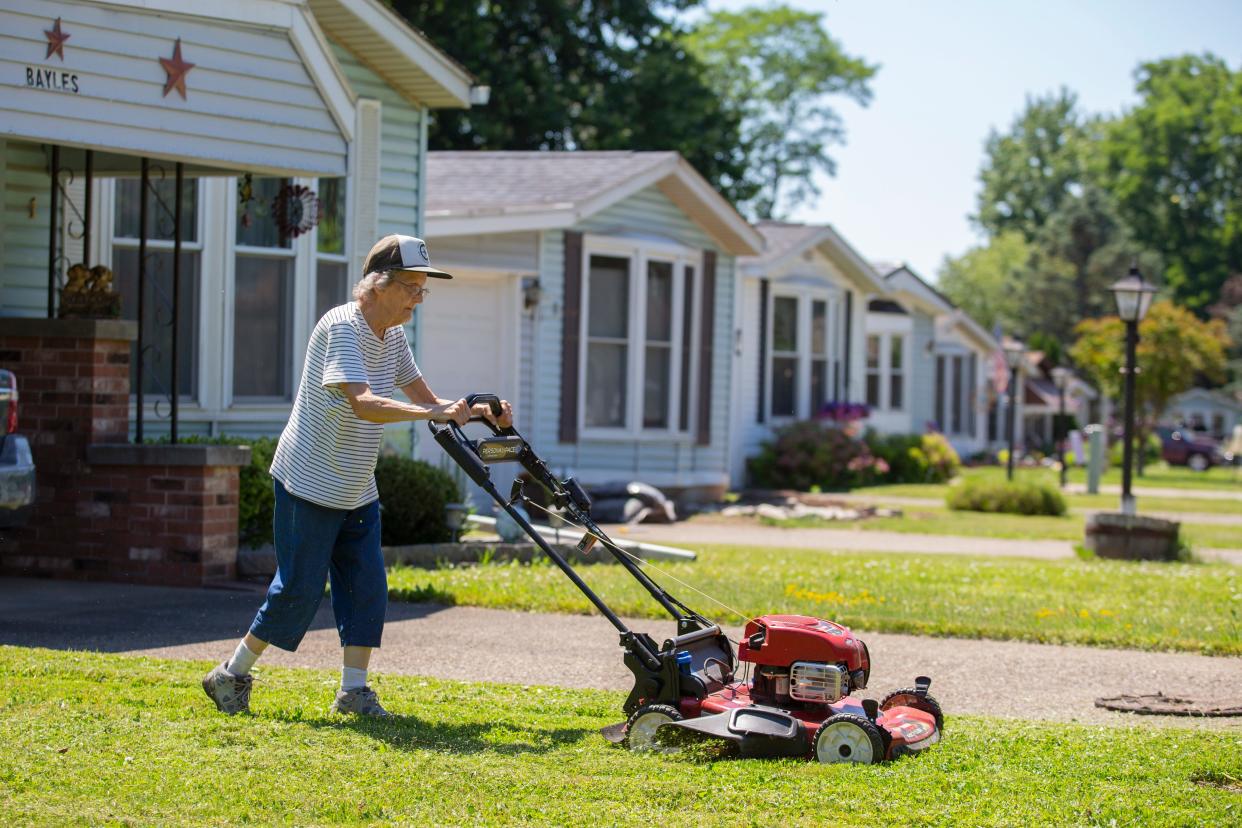 Joyce Bayles, 85, mows the lawn around her home in the Ridgeview Homes mobile home community in Lockport, N.Y. , June 23, 2022. The 85-year-old resident has taken to mowing her own lawn because crews for Ridgeview show up only monthly.