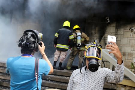 A journalist takes a selfie as firefighters extinguish burning tires after a demonstration against government privatisation plans in healthcare and education in Tegucigalpa