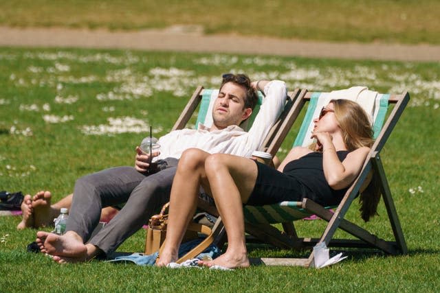 People sit in the sun in St James’s Park, central London