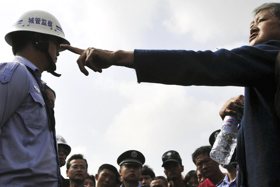 In this Aug. 12, 2008 photo, a street vendor, right, reacts during a standoff between officers of the urban management bureau, known as chengguan in Chinese, center, who allegedly beat up four street vendors, as angry vendors look on at a market in Kunming, in southwestern China's Yunnan province. The urban management bureau, a branch of city governments that China set up to monitor everything from unlicensed street vendors to unauthorized construction, is rife with abuse of power, stoking already high social tensions, a rights group said Wednesday. (AP Photo) CHINA OUT