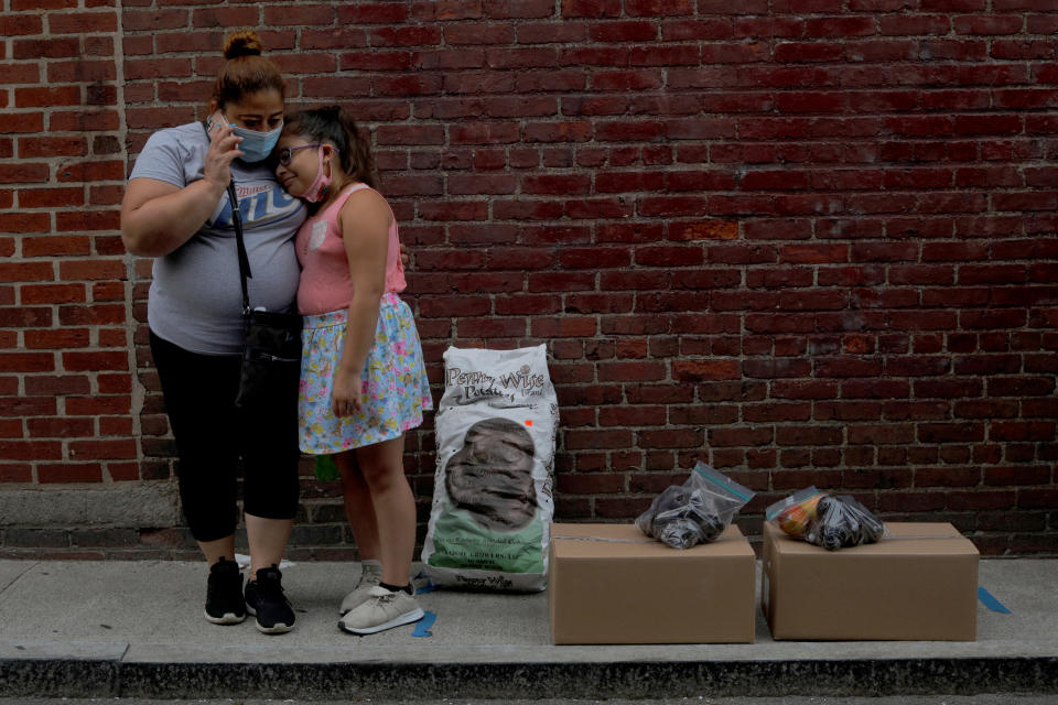 Sandra Cruz, who lost her job because of the coronavirus disease (COVID-19) outbreak, and fell four months behind on her rent and is fearing eviction, and her daughter Gabriella wait for a ride after picking up free groceries distributed by the Chelsea Collaborative in Chelsea, Massachusetts, U.S., July 22, 2020.   REUTERS/Brian Snyder     TPX IMAGES OF THE DAY